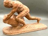 statue d'un homme sur une planche de surf, avec un rocher au premier plan