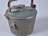 a small metal container with a handle on a white surface