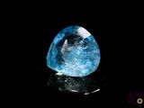 a close up of a blue diamond on a black surface