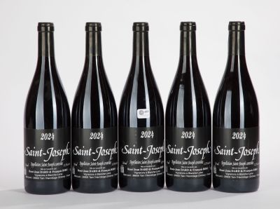 quatre bouteilles de vin sont alignées sur une surface blanche