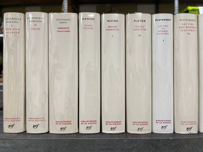 several white books are lined up on a shelf in a library
