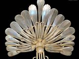 a silver peacock brooch on display against a black background
