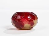 a red and gold vase sitting on a white surface