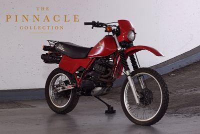 a red motorcycle parked in front of the pinnacle collection sign
