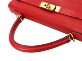 the red leather handbag has a gold clasp on the handle