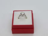 une photo d'une bague en diamant dans un écrin rouge posé sur une surface blanche