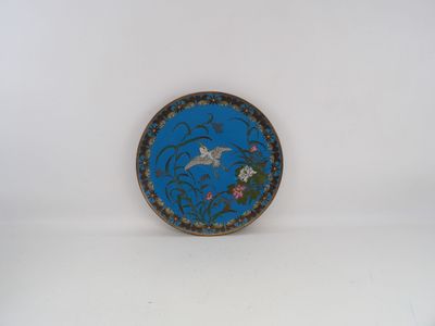 une assiette bleue ornée d'un oiseau, sur un fond blanc