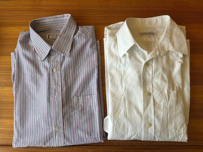 two men ' s shirts sitting on a wooden table next to each other