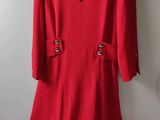 a red dress hanging on a hanger against a white wall