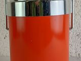 an orange and silver ice bucket sitting on top of a table