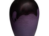 un vase noir et violet posé sur une surface blanche