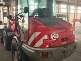 a red and black tractor parked in a warehouse