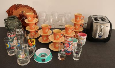 de nombreuses tasses et soucoupes posées sur une table où se trouvent un grille-pain et un autre grille-pain