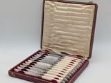 an open case with six knives in it sitting on a white surface