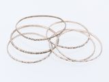 a close up of a stack of silver bangles on a white surface