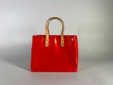 a red handbag sitting on top of a white surface