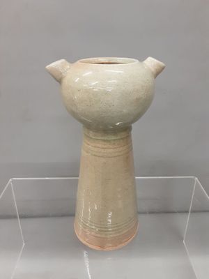 a white vase on display on a clear shelf