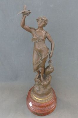 statue en bronze d'une femme tenant un oiseau sur un socle en marbre
