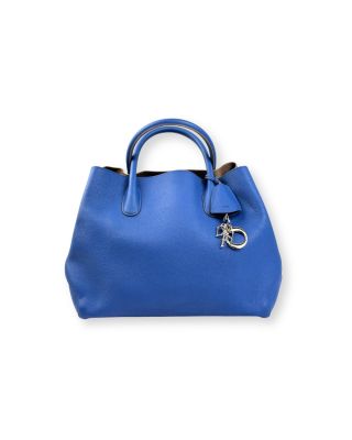un sac à main bleu muni d'une poignée en métal sur fond blanc