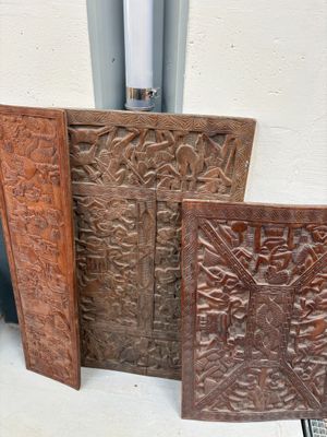 Plusieurs objets sculptés en bois sont posés sur une table près d'une fenêtre