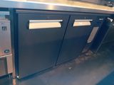 a metal counter with two doors and a refrigerator in the kitchen
