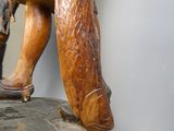 une statue représentant un homme tenant un poisson sur un rocher