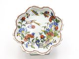 un bol blanc orné de fleurs et d'oiseaux colorés