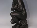 a statue of a man kneeling down with his hands on his knees