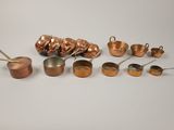 an assortment of copper pots and pans on a white surface