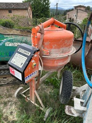 une bétonnière orange garée dans la cour, à côté d'une roue verte