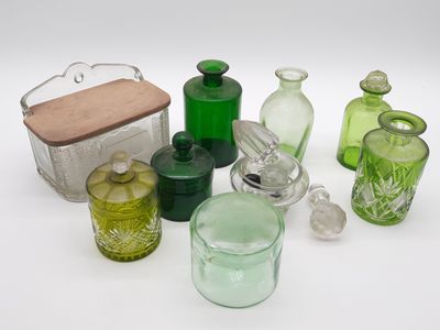 de nombreuses bouteilles et récipients en verre de différentes couleurs posés sur une surface blanche