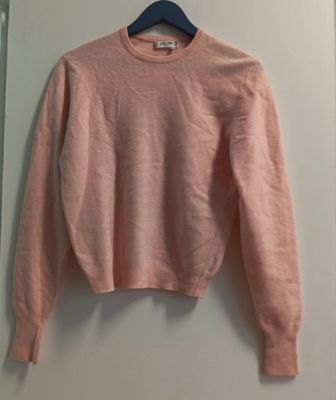 un pull rose accroché au mur à côté d'un miroir