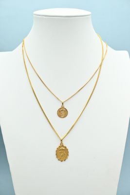 a gold necklace with two medallions on a mannequin