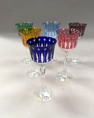 four different colored wine glasses sitting on top of a white table