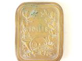 a small metal box with a gold label on it