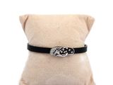 black leather bracelet with a silver buckle on a white pillow