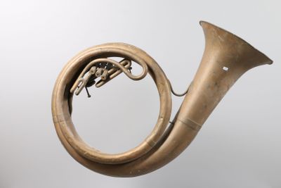 an old brass french horn on a stand against a white background