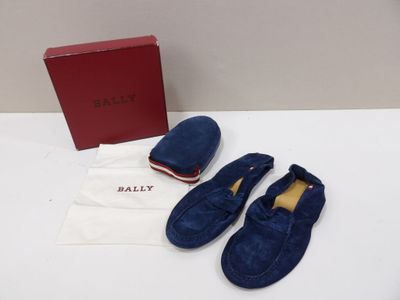 une paire de chaussures en daim bleu et une boîte rouge posées sur une table