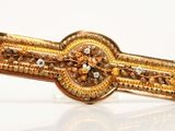 a gold tie bar with a brown and white diamond