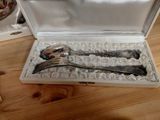 two silver spoons in a box on a table