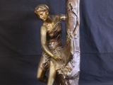 bronze statue of a woman sitting on a tree branch