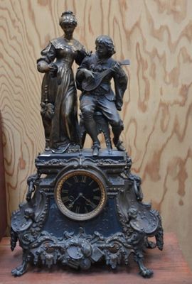 une statue en bronze représentant un homme et une femme sur une horloge