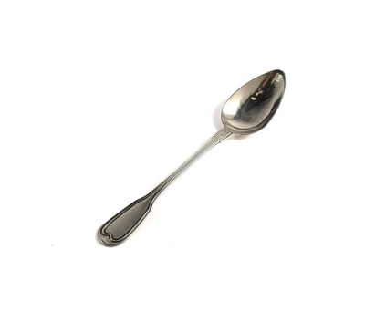 une cuillère en argent avec un manche de cuillère sur une surface blanche
