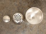an overhead view of a sink with a strainer and soap dispenser