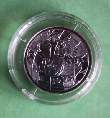 a silver coin in a plastic container on a green surface
