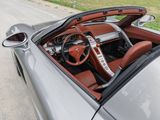 the interior of a silver sports car with a red leather seat