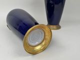 two blue vases with gold rims on a white surface