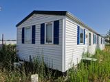 une petite maison blanche aux volets bleus, au milieu d'un champ