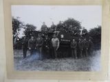 photograph of a group of men standing in front of a military vehicle