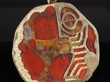 un gros plan d'un pendentif rouge et doré sur une surface noire